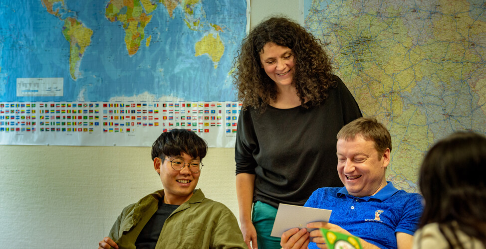 Un professeur qualifié avec des étudiants en cours d'allemand à la DIE NEUE SCHULE Berlin devant des cartes